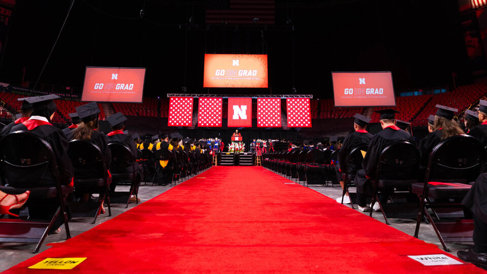 Commencement stage flanked by rows of graduates in August 2025 Commencement
