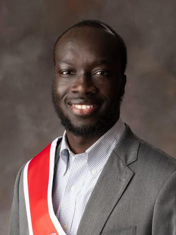 Studio portrait of student wearing gray jacket and red sash