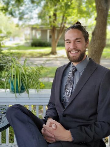 Graduate wearing suit portrait outside in front of house