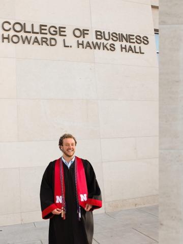 Graduate in gown outside Hawks Hall