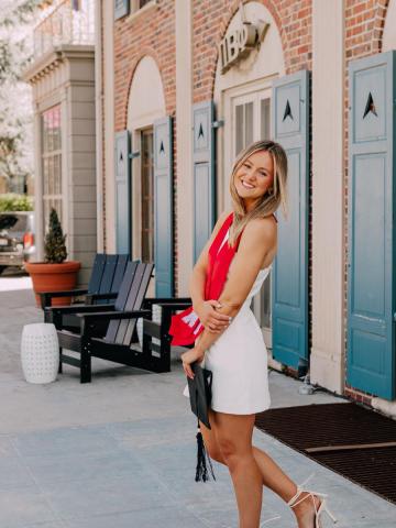 Graduate standing in front of sorority house