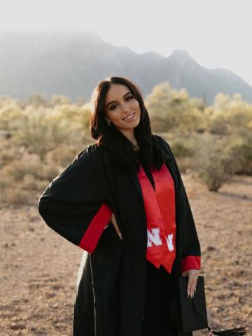 Graduate in robe standing in front of hills