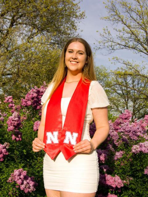 Grad in sash in front of blooming flowers