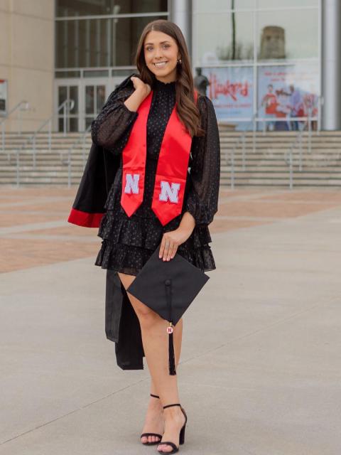 Student with cap and gown outside Memorial Stadium