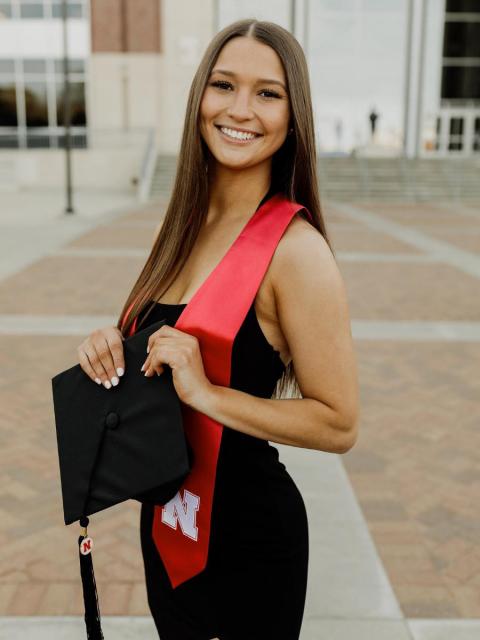 Graduate in black dress with cap outside Memorial Stadium